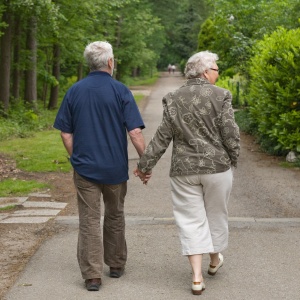 Old-couple-walking-outdoors-on-path-near-tree1